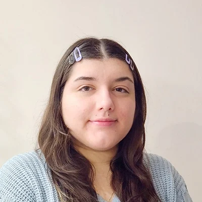 Office Manager Karina Smiling In Front Of Grey Wall