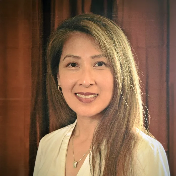 Eye Doctor Sharon Than Smiling In Front Of Brown Curtain